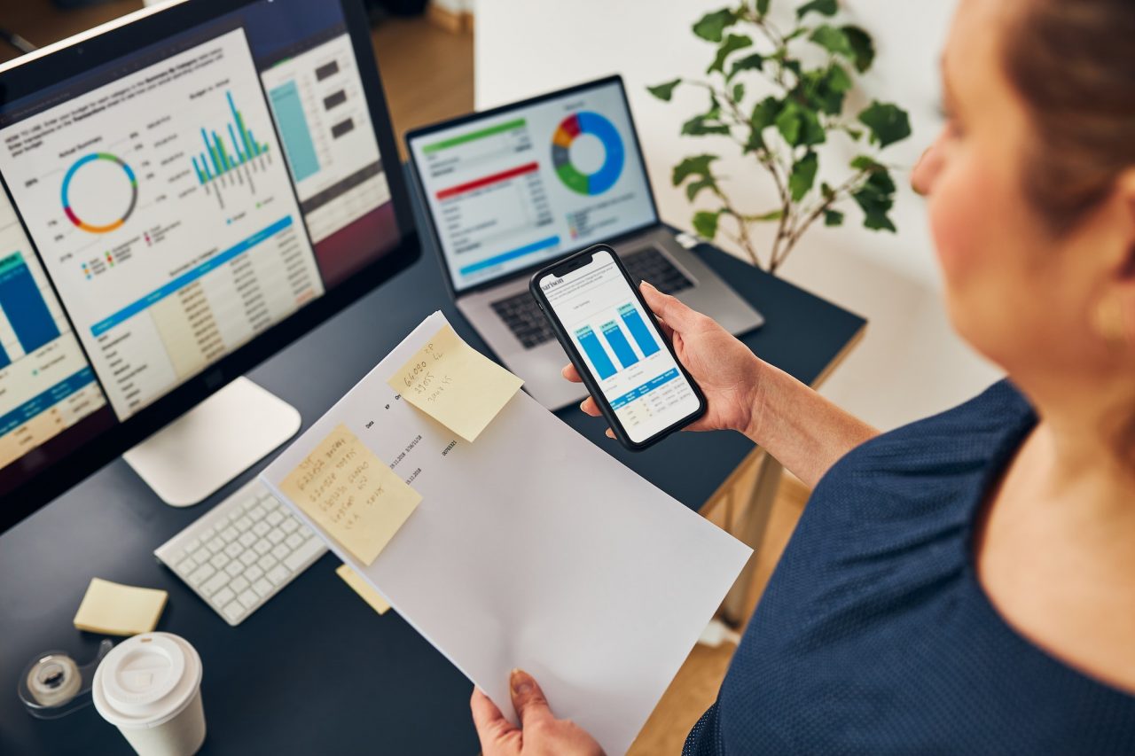 businesswoman-working-with-financial-data-on-charts-and-tables-on-smartphone-and-computer